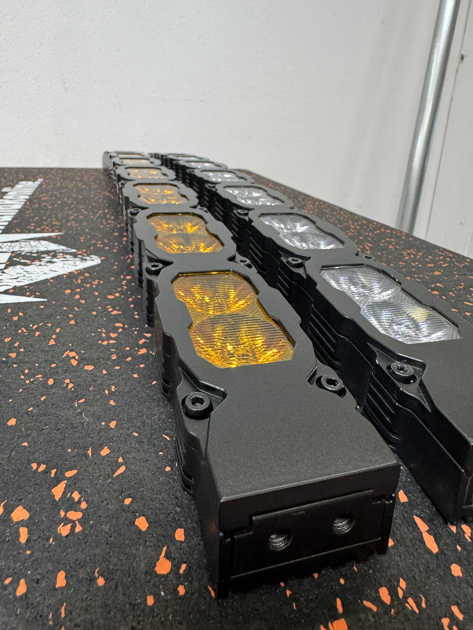 Row of black LED light bars on a black surface with orange specks.