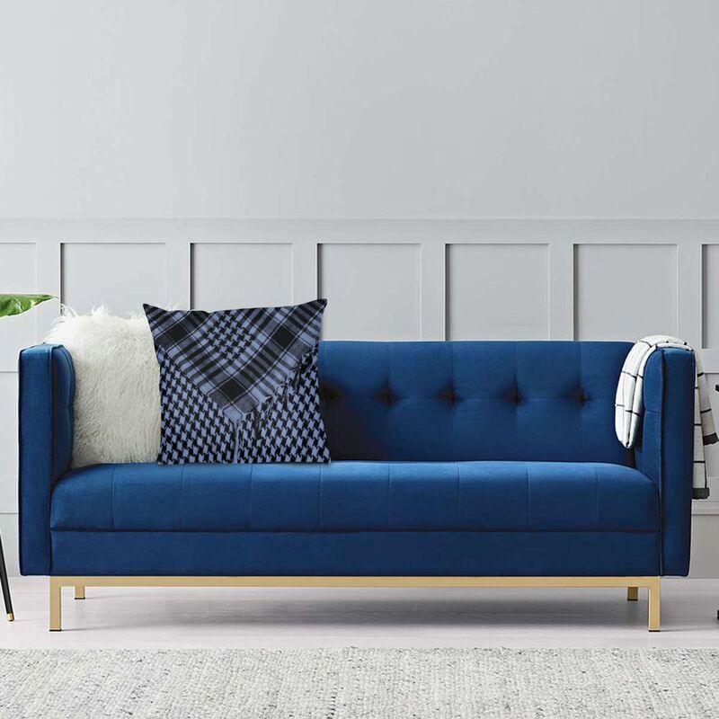 Blue sofa with decorative pillows and a blanket against a light gray wall.
