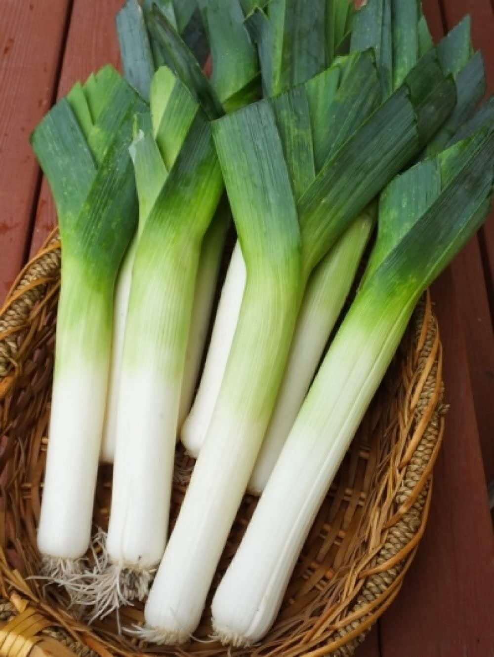 Leeks in a woven basket on a wooden surface