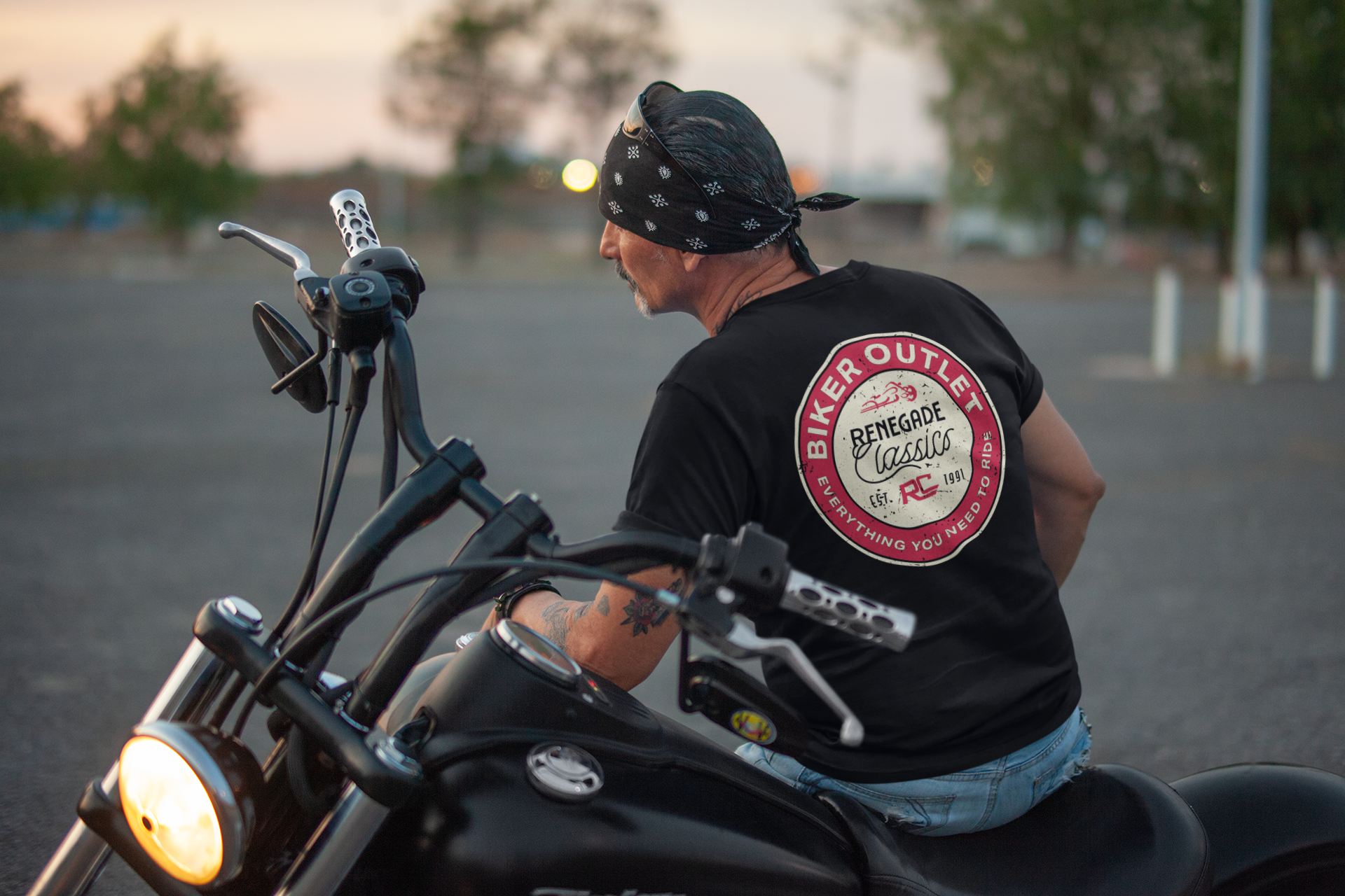 Biker wearing Black crew neck t-shirt with a round red and white 'Biker Outlet Renegade Classics' print on the  back sitting on his motorcycle