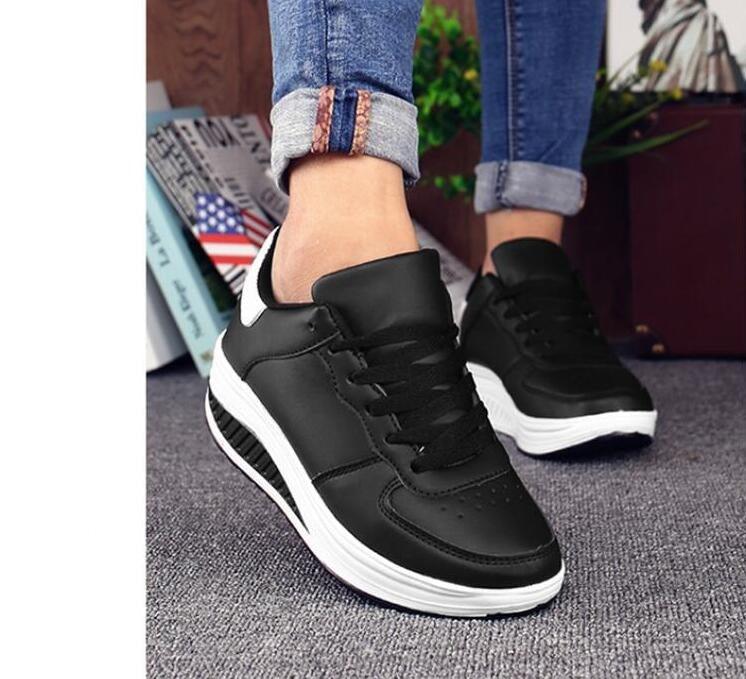 Black sneakers with white soles worn by a person, with jeans rolled up.