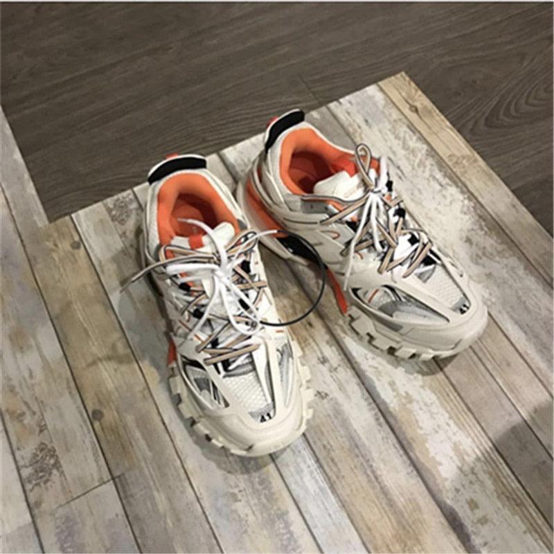 White sneakers with orange accents on a wooden floor