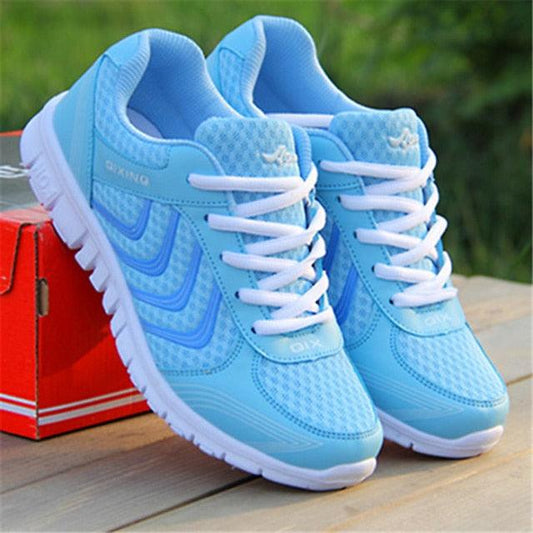 Pair of blue running shoes with white laces on a wooden surface.