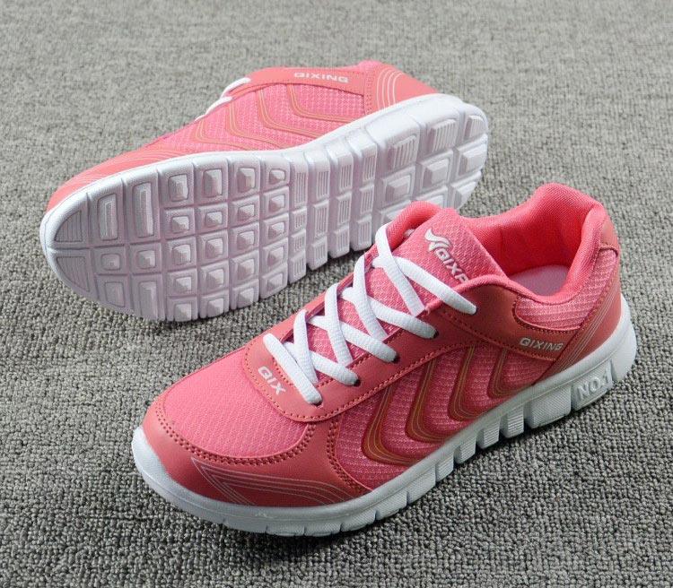 Pink running shoes with white soles on a gray surface