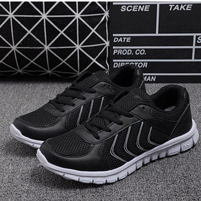 Black athletic shoes on a gray surface with a geometric patterned rug in the background.