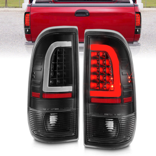 Pair of black and red car tail lights with a red truck in the background.
