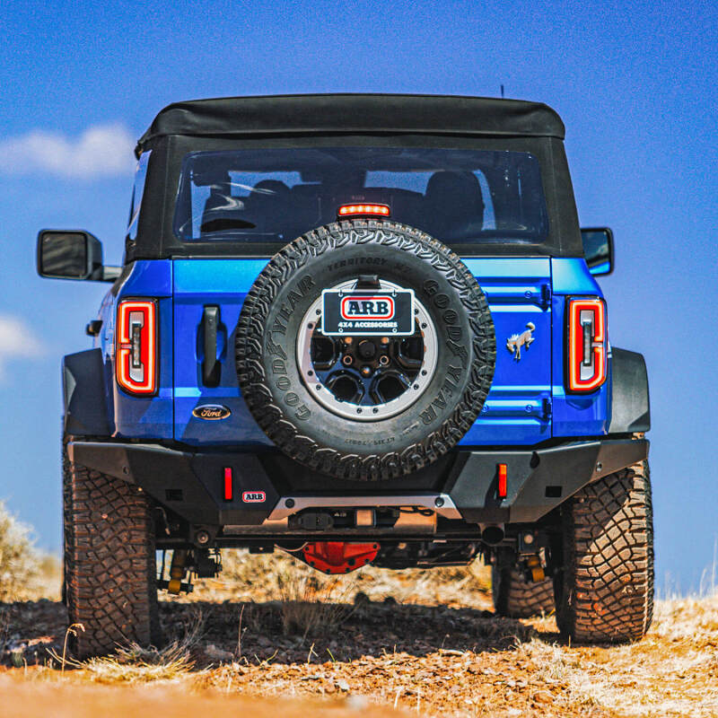 Blue off-road vehicle with spare tire and 'ARB' branding on a clear day.