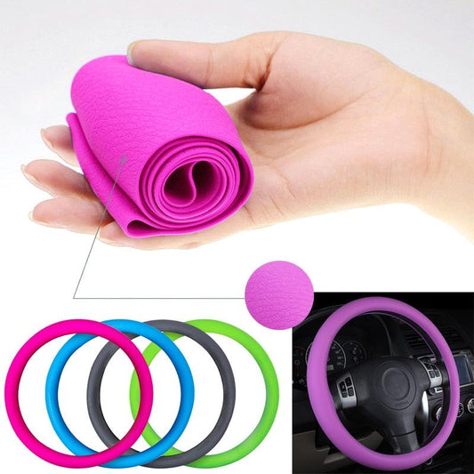 Hand holding a pink steering wheel cover with additional covers in different colors displayed.