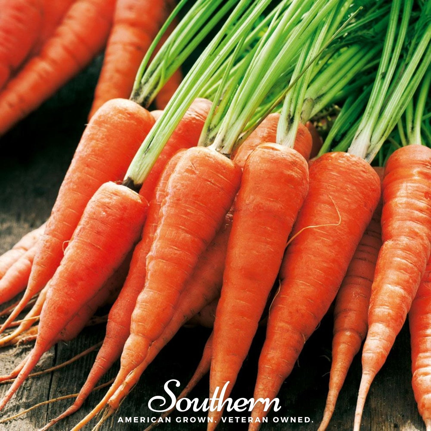 Bunch of fresh carrots with green tops on a wooden surface, featuring the 'Southern' brand.