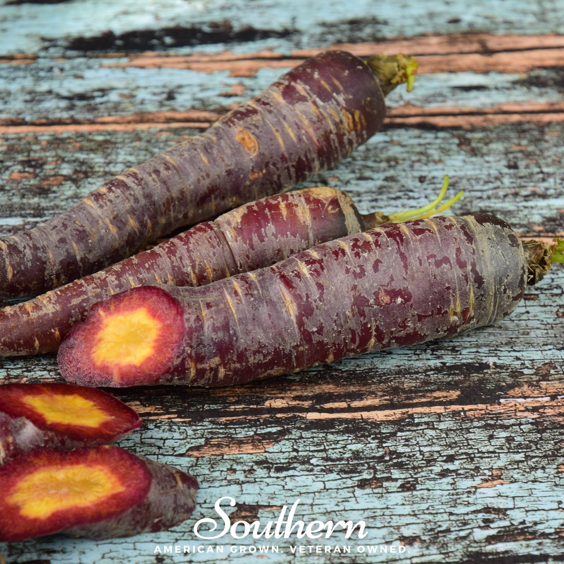 Purple carrots with a cut one showing orange interior on a rustic wooden surface, branded 'Southern'.