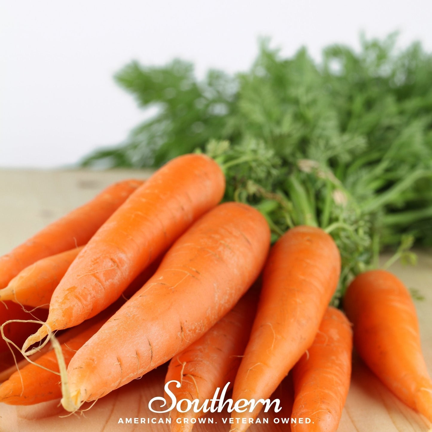 Bunch of carrots with green tops on a wooden surface, featuring the 'Southern' brand.