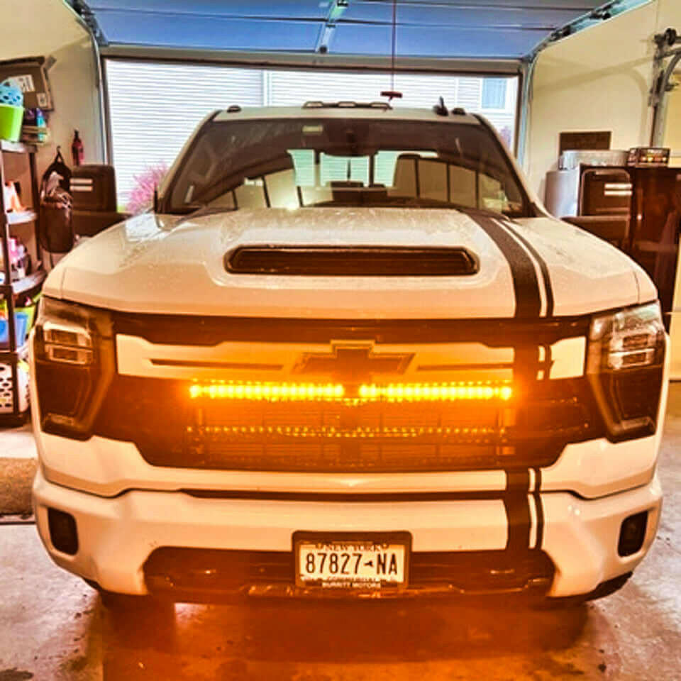White Chevrolet truck with a large LED light bar in a garage.