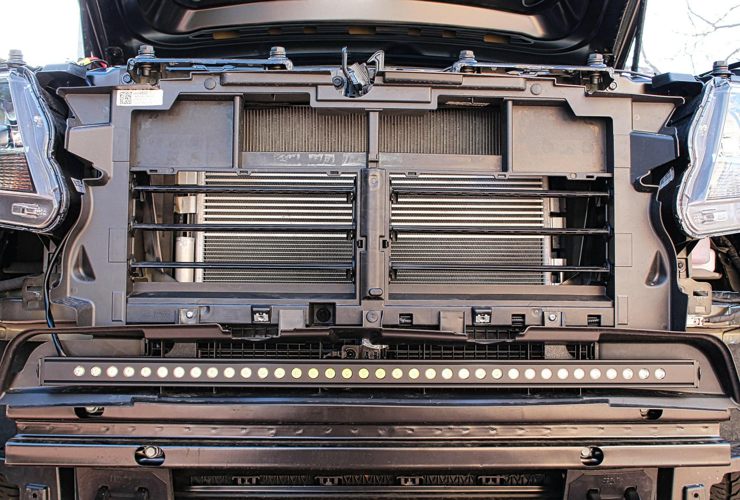 Close-up of a vehicle's open hood with a focus on the engine and LED light bar.