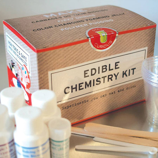 Edible chemistry kit with box, test tubes, and popsicle sticks on a white background