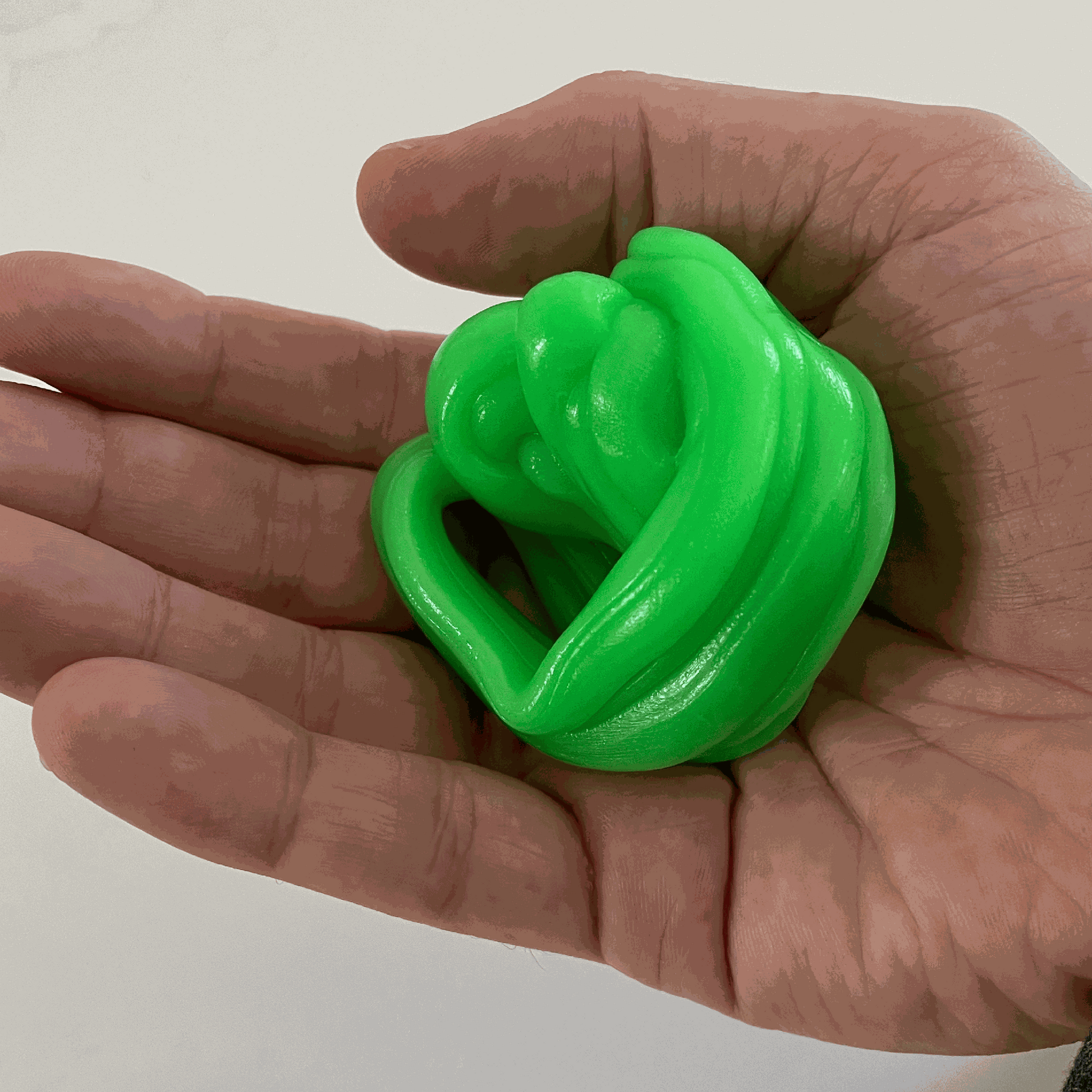 Hand holding green gootonium putty against a plain background