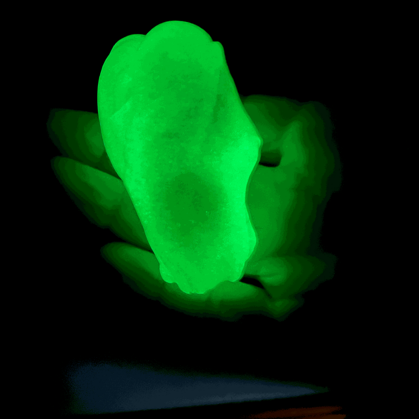 Glowing green gootonium held on a black background