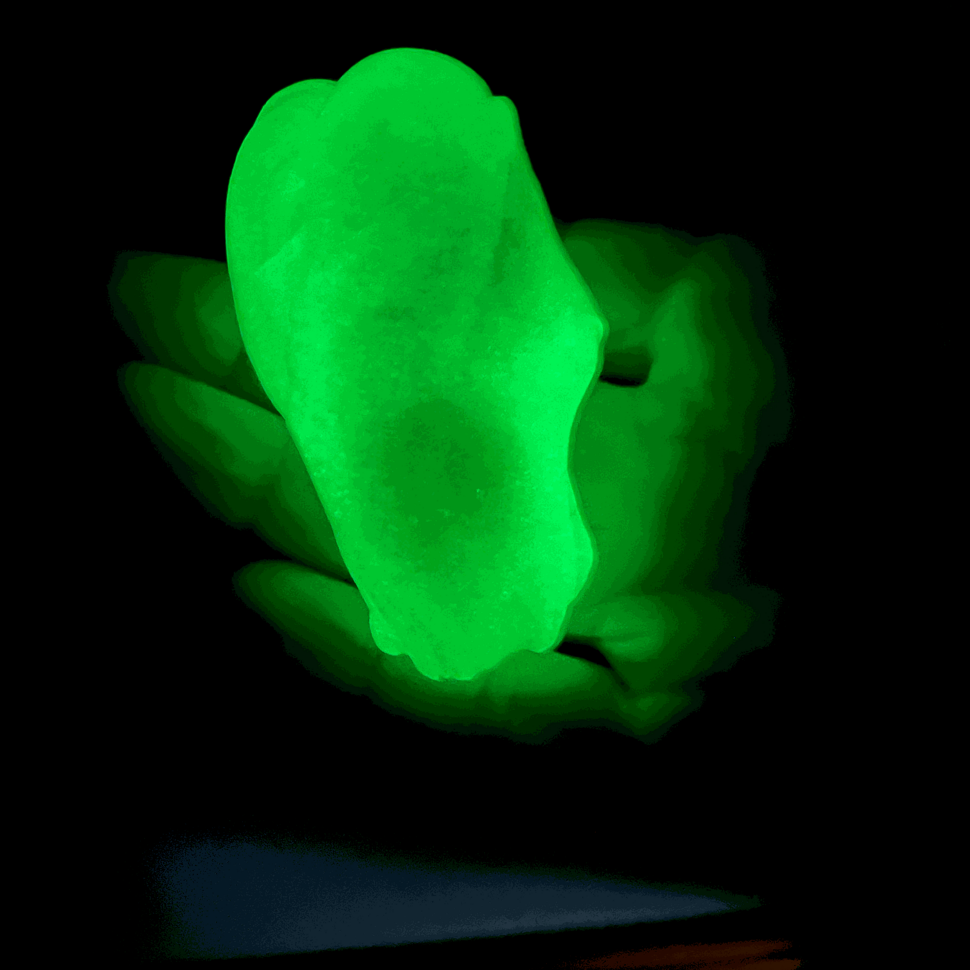 Glowing green gootonium held on a black background