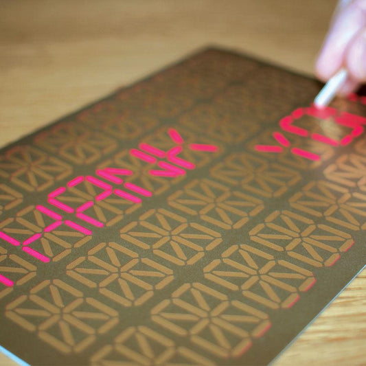 Sheet of paper with red text and geometric pattern on a wooden surface