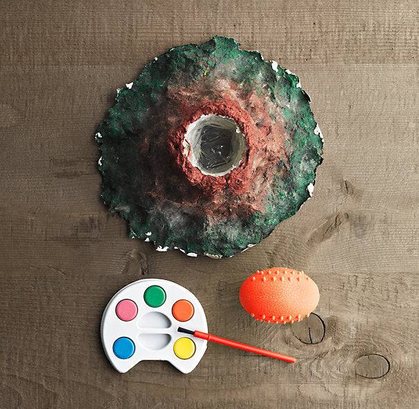 Artistic depiction of a volcano kit with a paint palette and brush on a textured surface