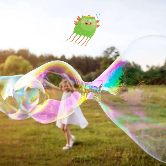 Child in a white dress playing with large soap bubbles in a field with a green monster toy in the sky.