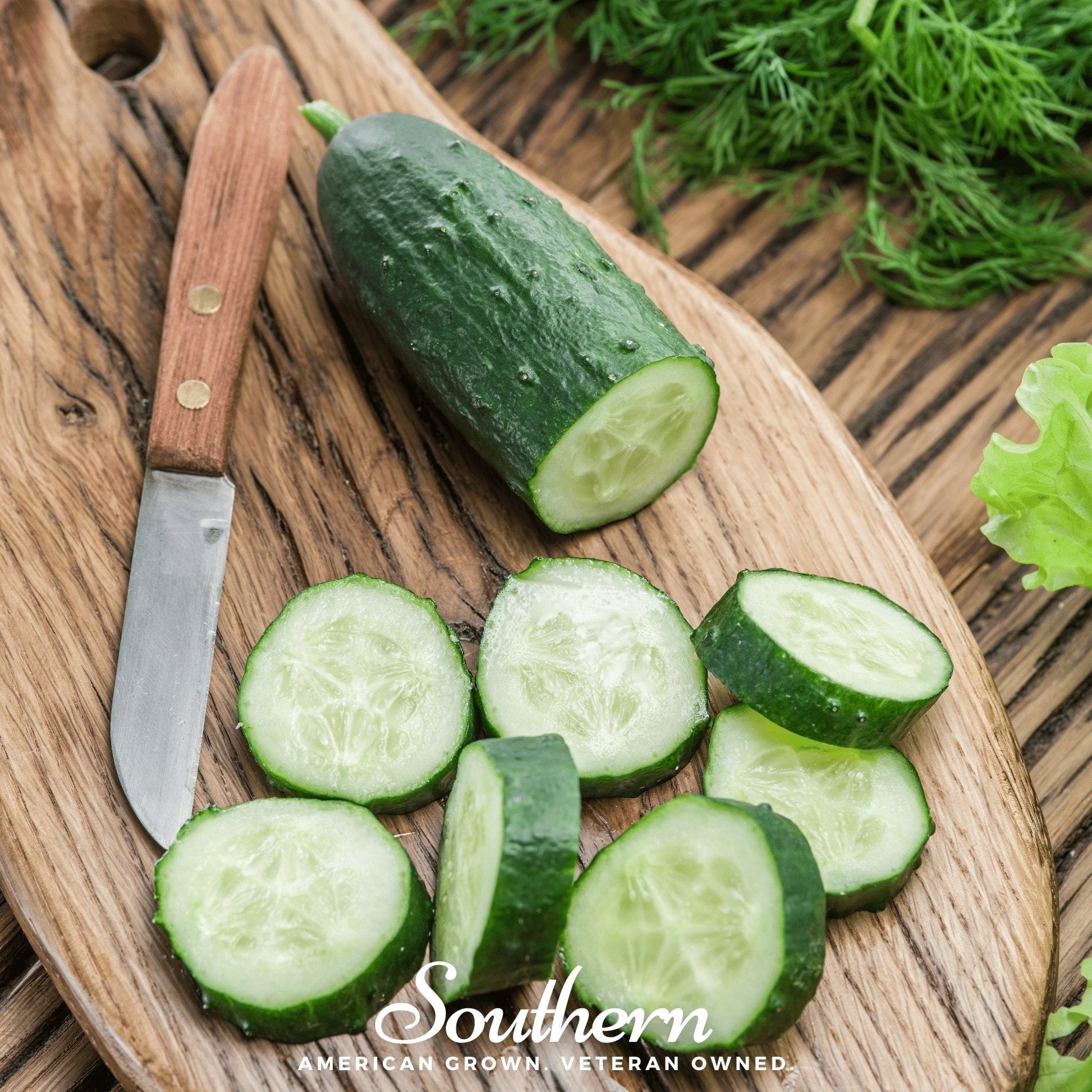 Sliced cucumbers on a wooden cutting board with a knife and fresh herbs.