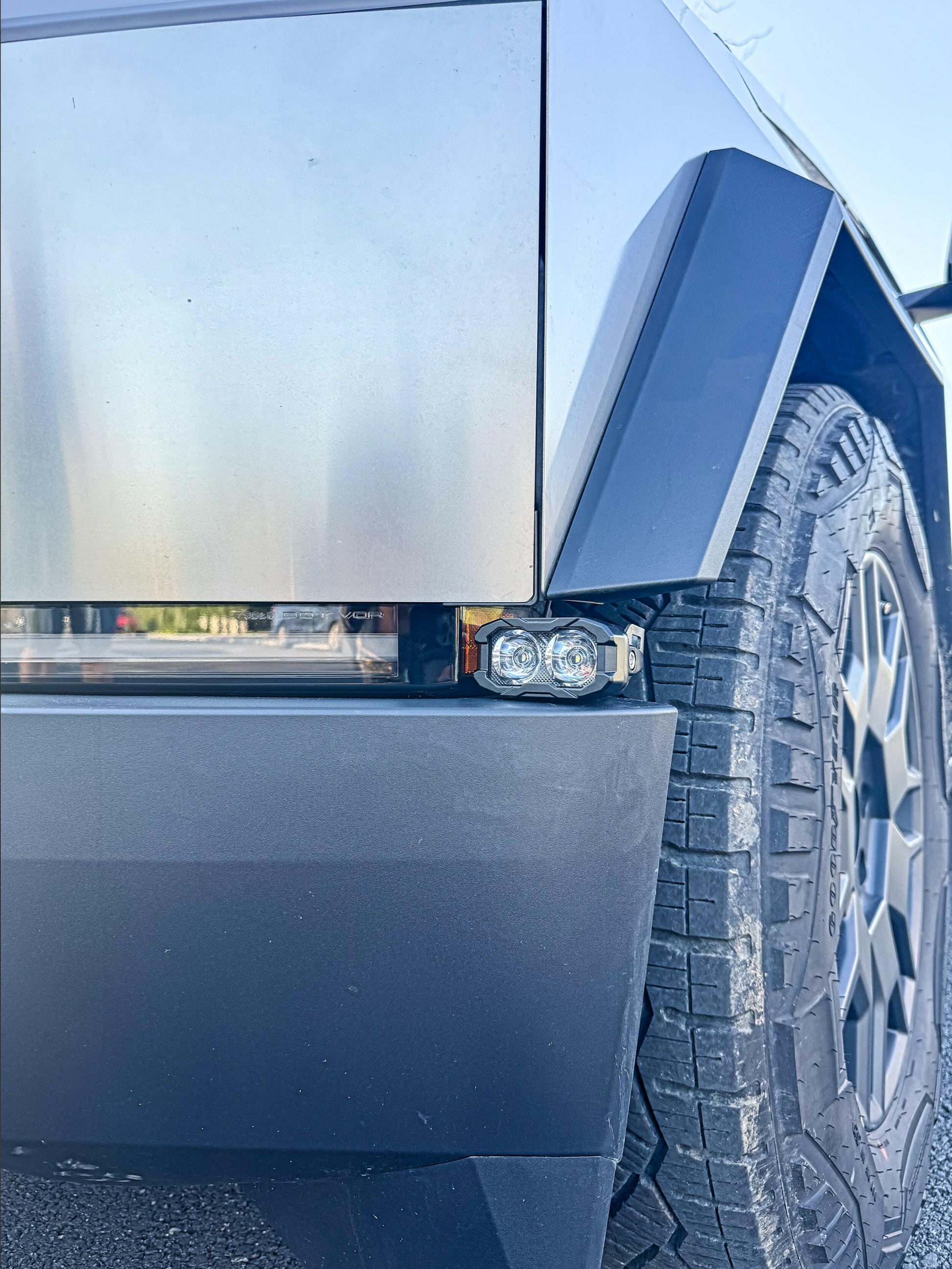 Close-up of a tesla vehicle's front fender and tire with a mounted lighting