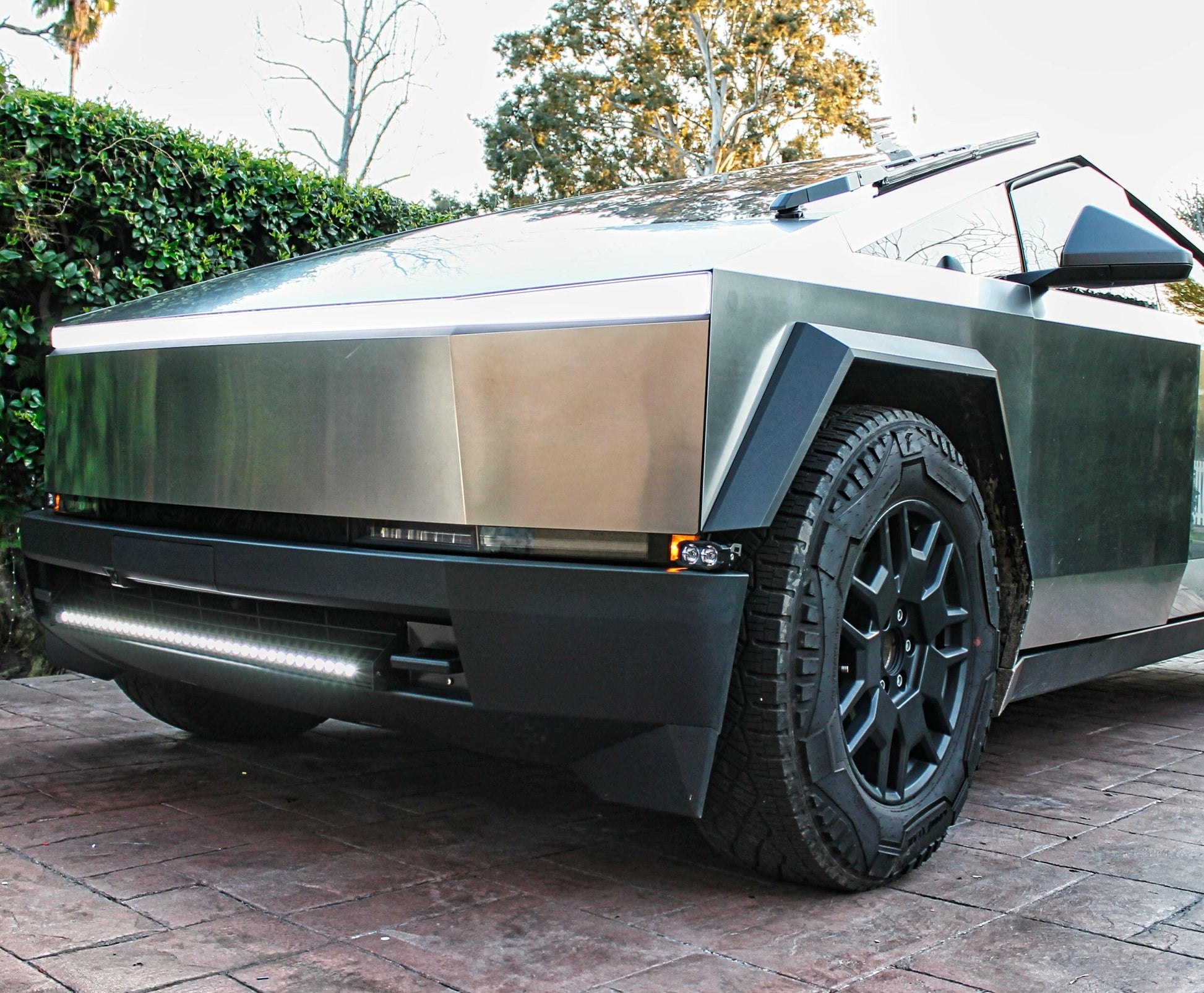 Modern electric vehicle on a paved surface with greenery in the background and a Bumper Light Pod