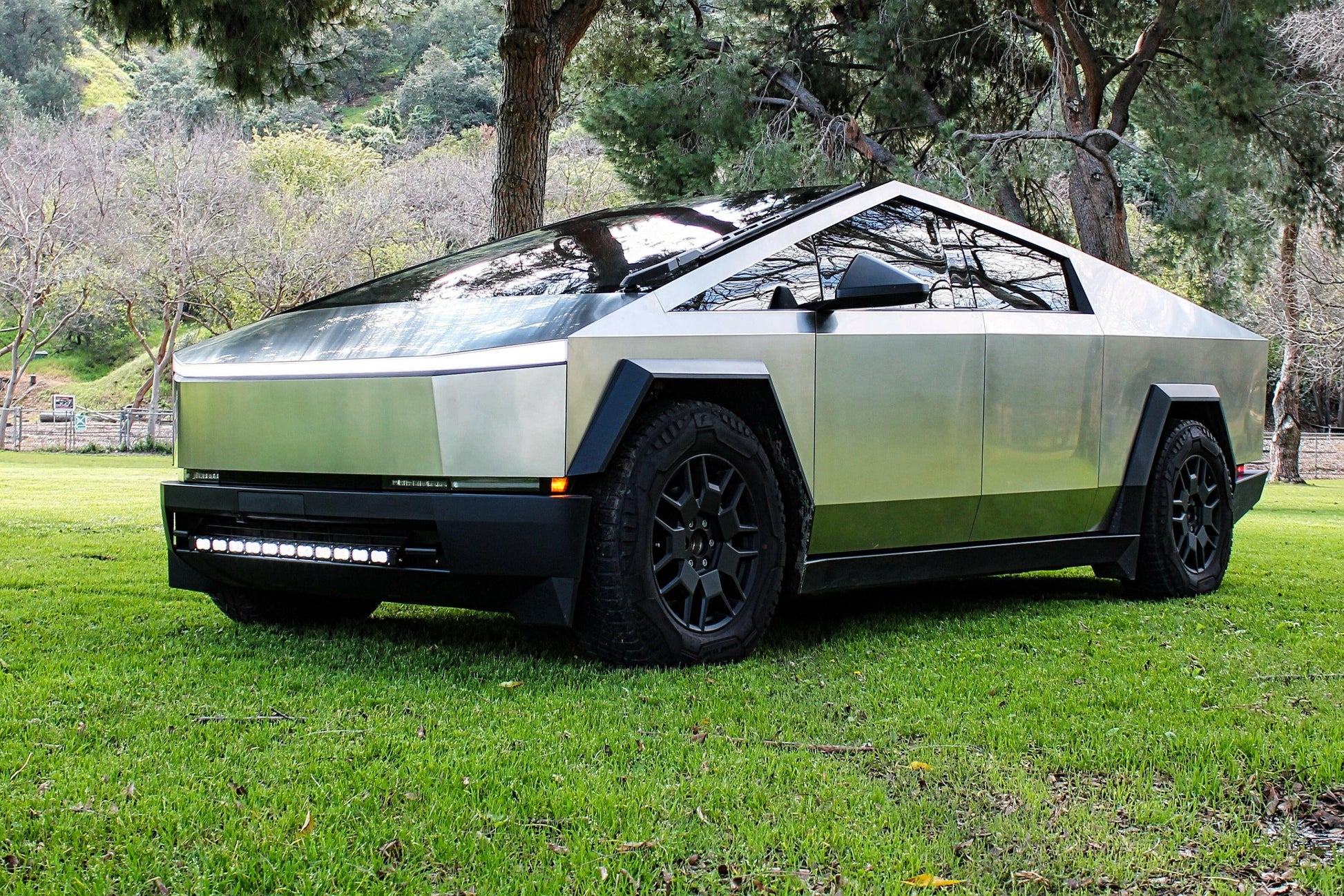 Tesla Cybertruck on a grassy area with trees in the background