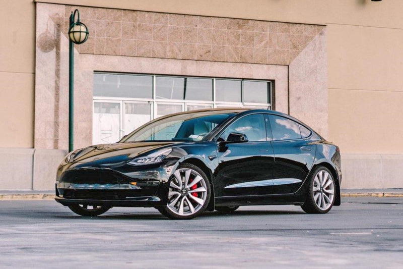 Black Tesla car parked in front of a building
