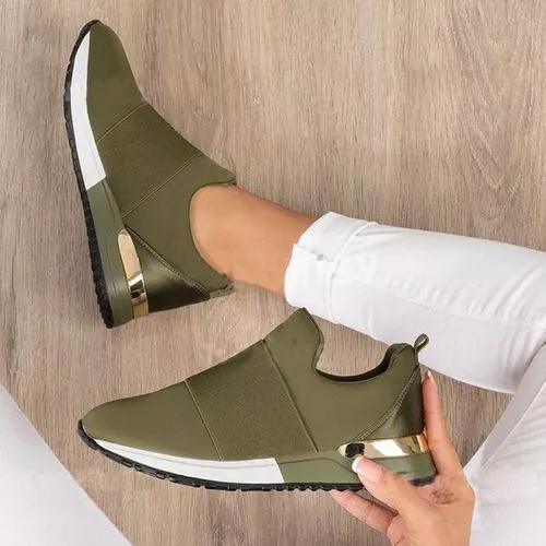 Person wearing green slip-on shoes with a wooden floor background