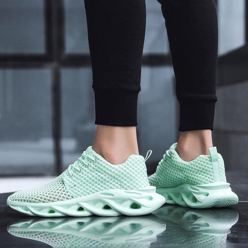 Light green sneakers worn with black pants on a reflective surface.