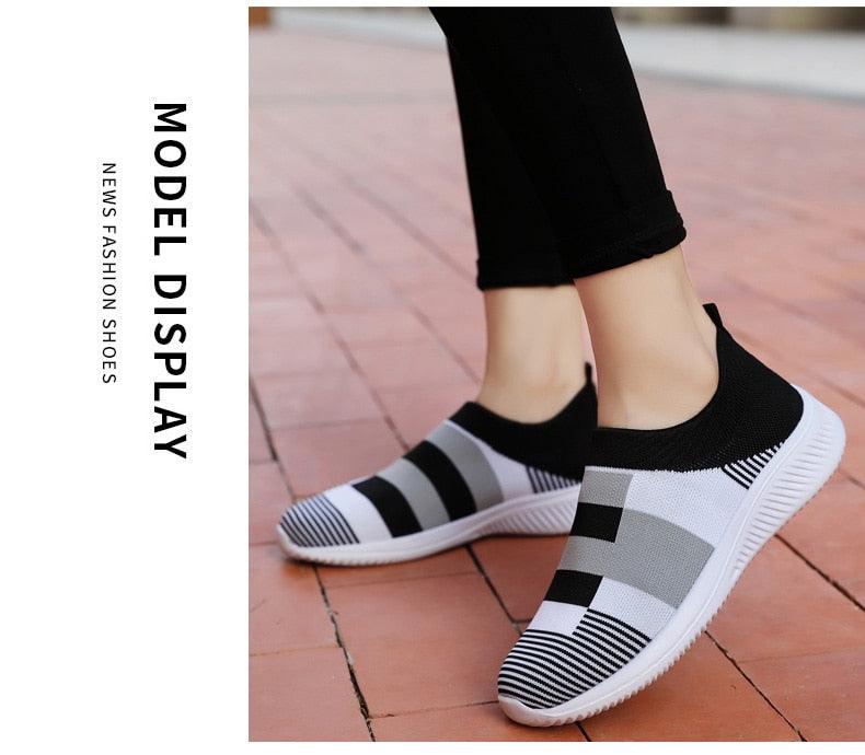 Black and white checkered slip-on shoes worn by a person on a tiled floor.