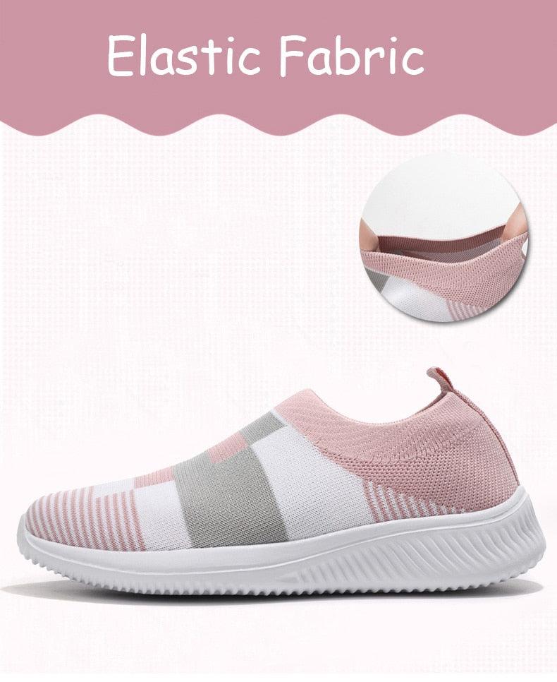 Pink and gray sneaker with white sole on a light pink background, highlighting elastic fabric.
