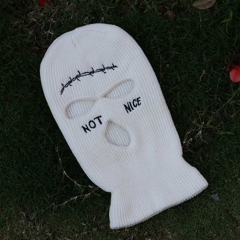 White balaclava with 'Not Nice' text on a grassy background