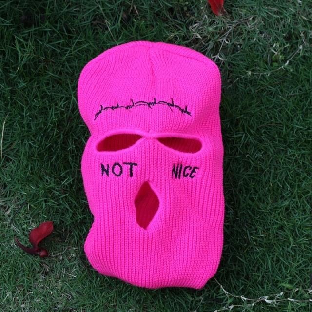 Pink balaclava with text on a grassy background
