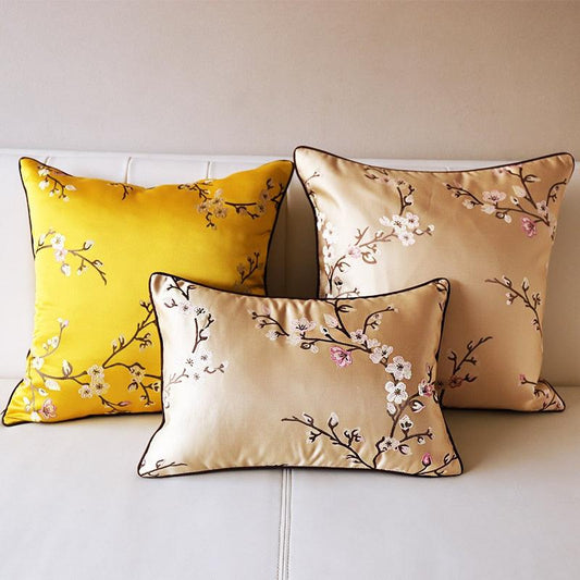 Three decorative pillows with floral patterns on a light-colored sofa.
