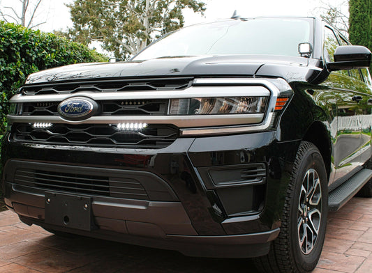 Black Ford truck with  LED Light Bars  parked on a brick driveway with greenery in the background