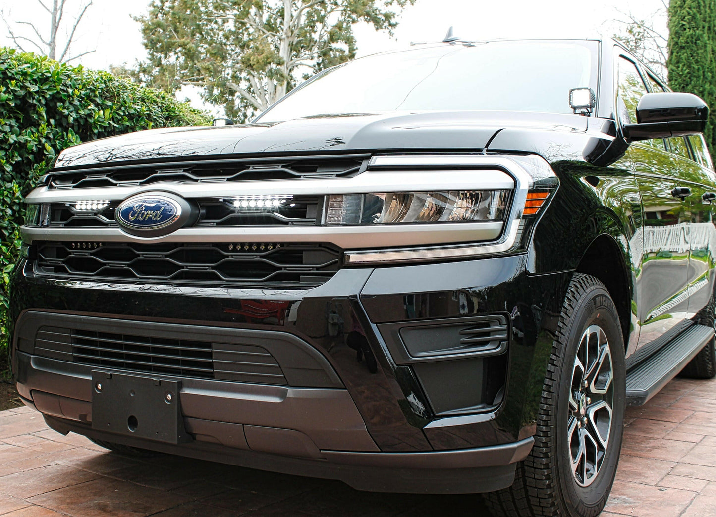 Black Ford SUV with LED Light Bars parked on a driveway with greenery in the background