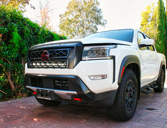 White pickup truck with black accents on a paved surface with greenery in the background and LED Light Bars