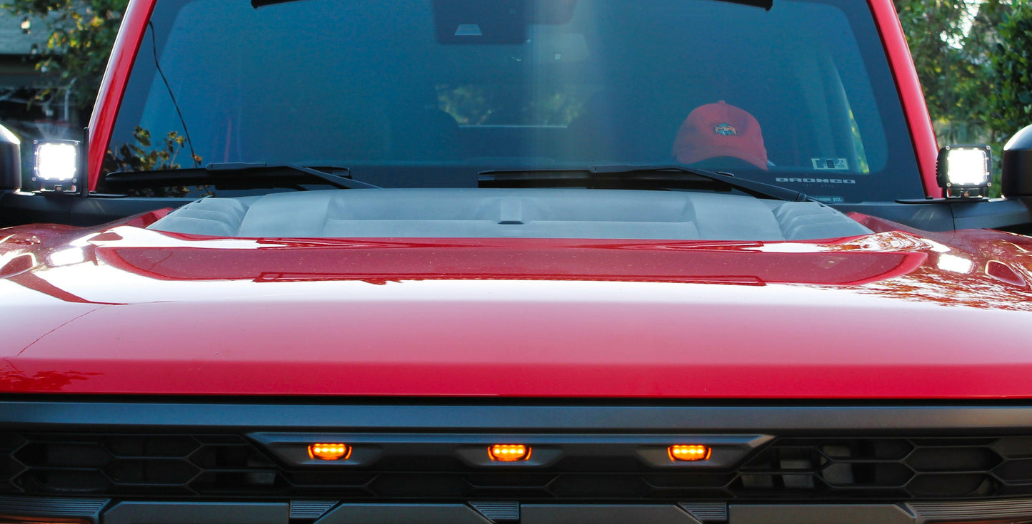 Close-up of a red vehicle's hood with visible lights and windshield.