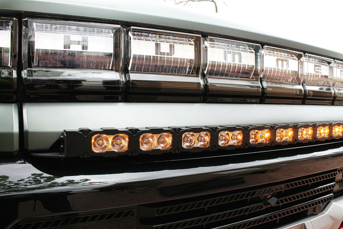 Close-up of a hummer vehicle's front grille with LED lights and a chrome bar.