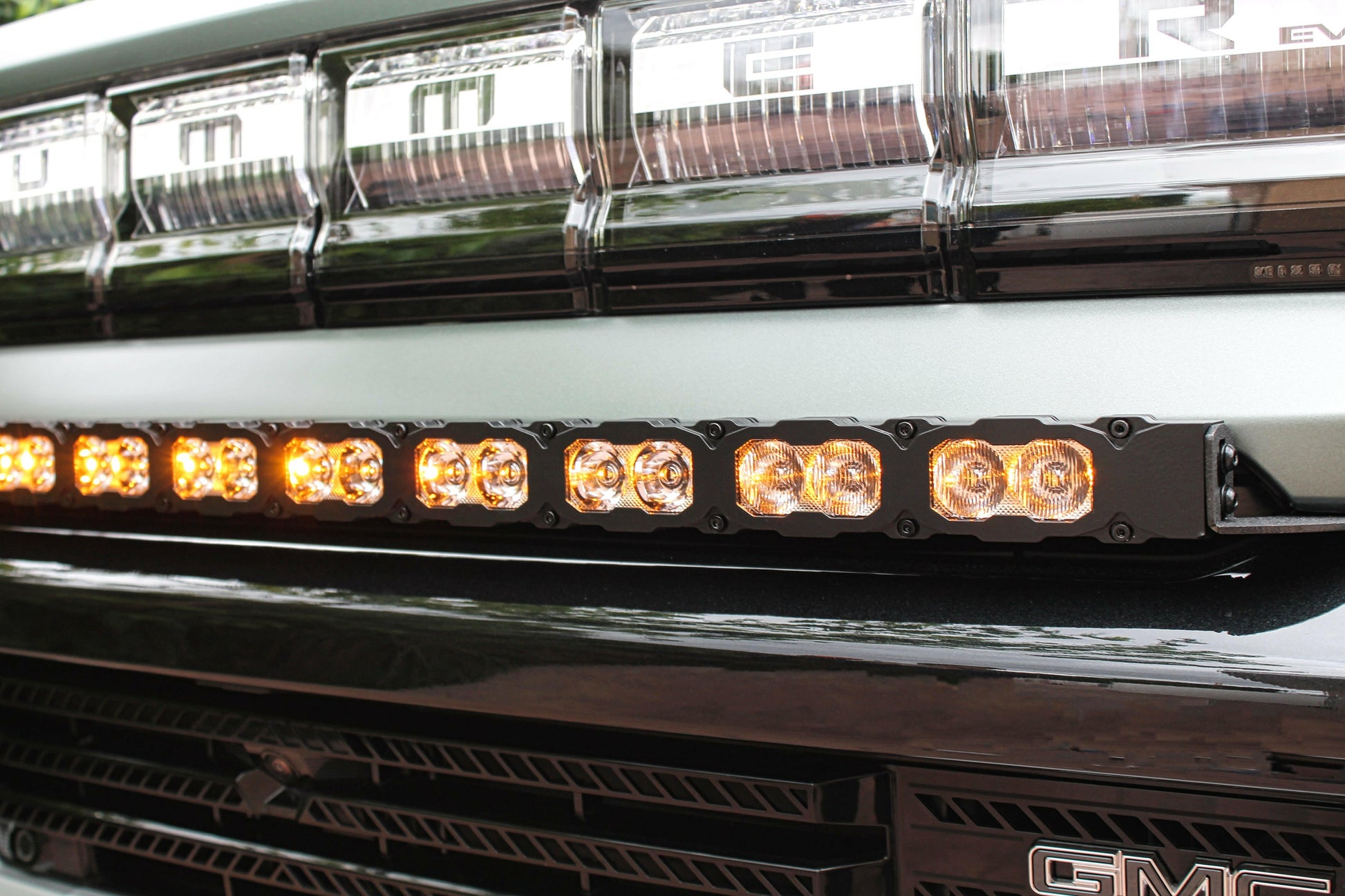 Close-up of a GMC vehicle with a prominent LED light bar on the grille.