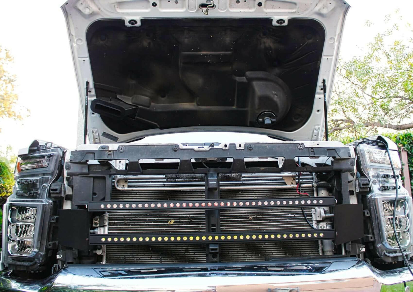 Car with open hood showing engine components and LED Light bars outdoors