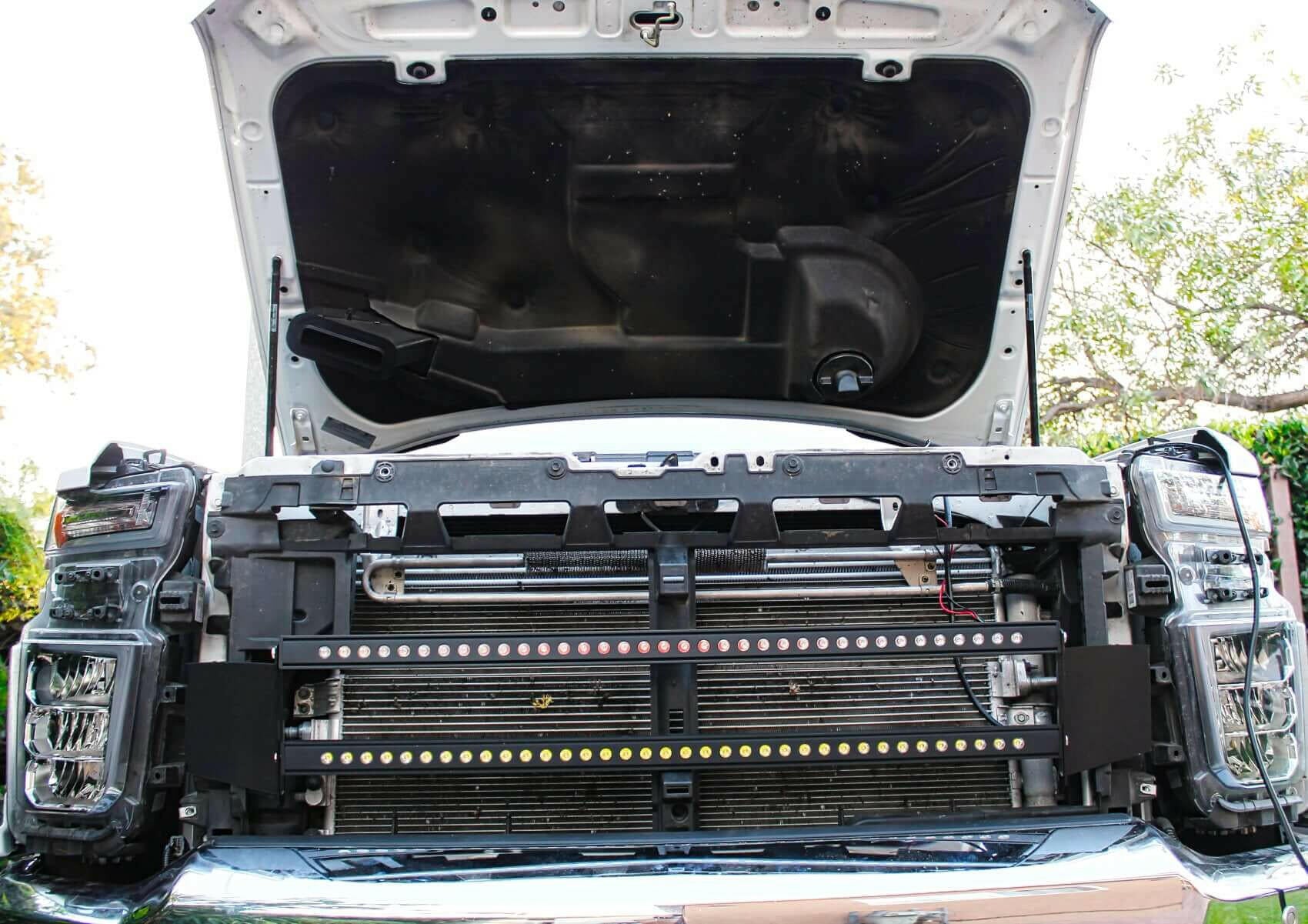 Car with open hood showing engine components and LED Light bars outdoors