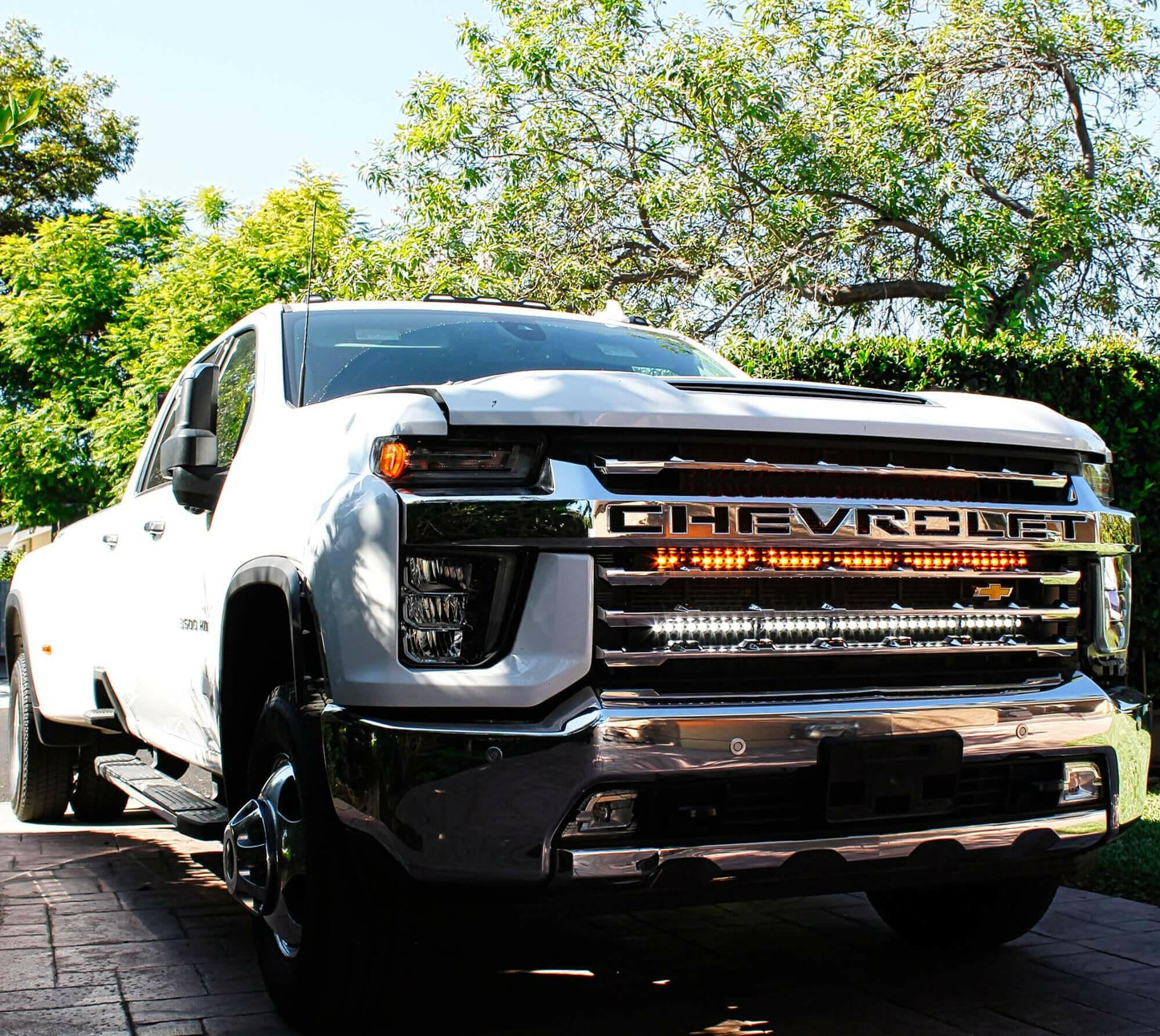 White Chevrolet truck parked on a driveway with trees in the background