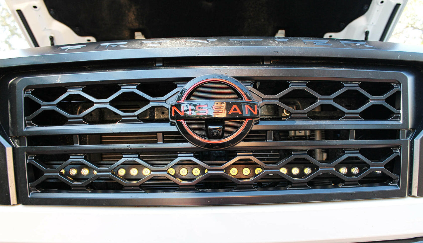 Nissan logo on a car grille with a black honeycomb design over LED Light Bars