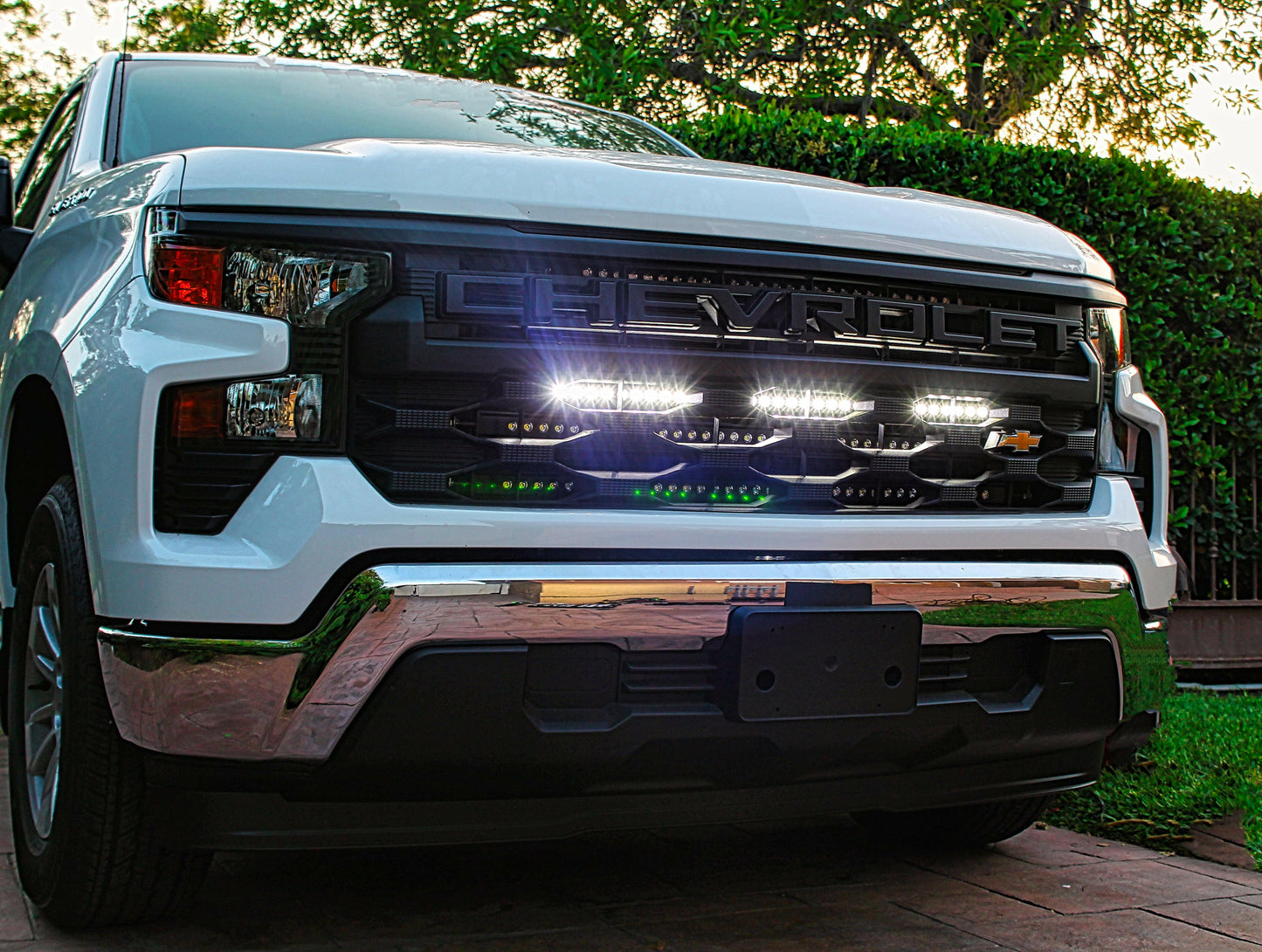 Front view of a white Chevy truck with illuminated LED Light Bar on a driveway.