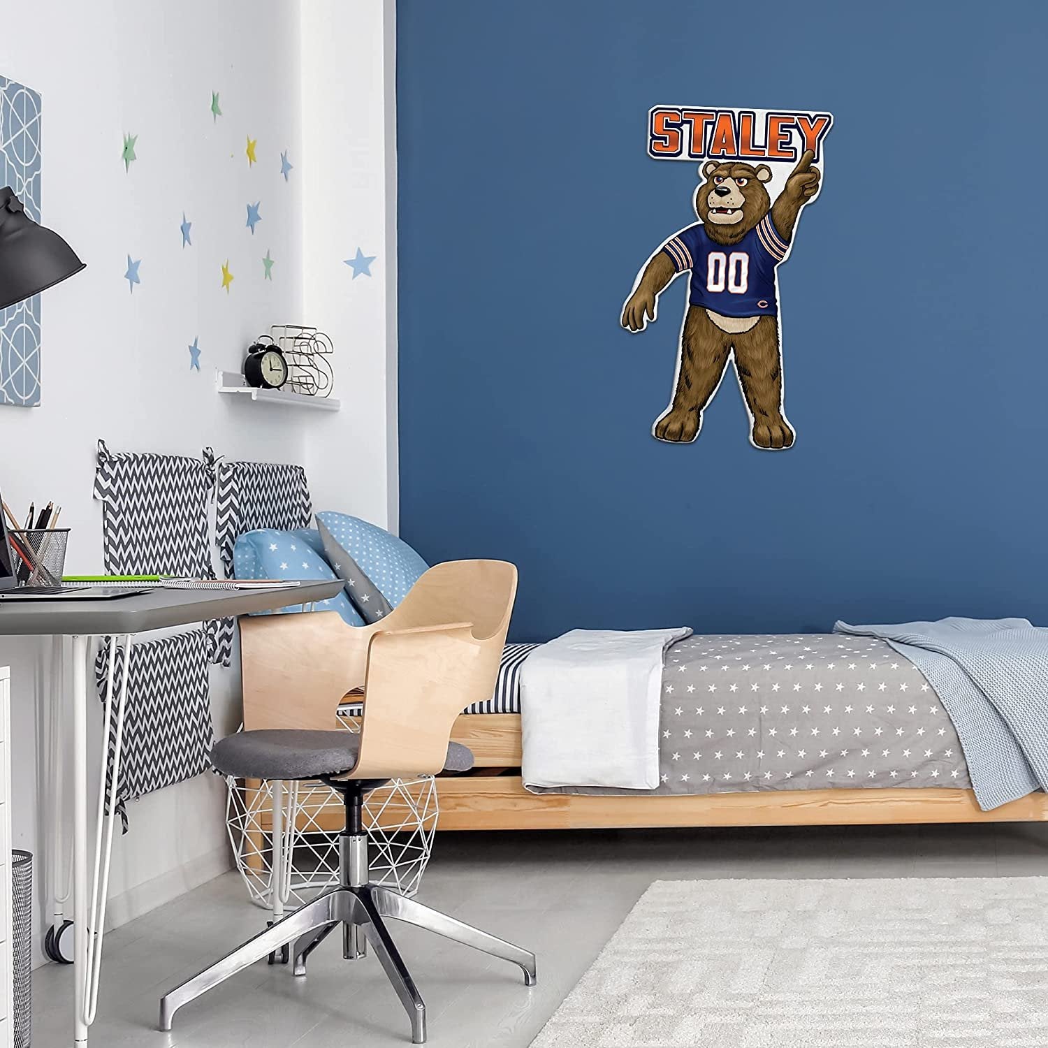 Bedroom with a desk, chair, and bed, featuring a 'Staley' bear mascot on the wall.