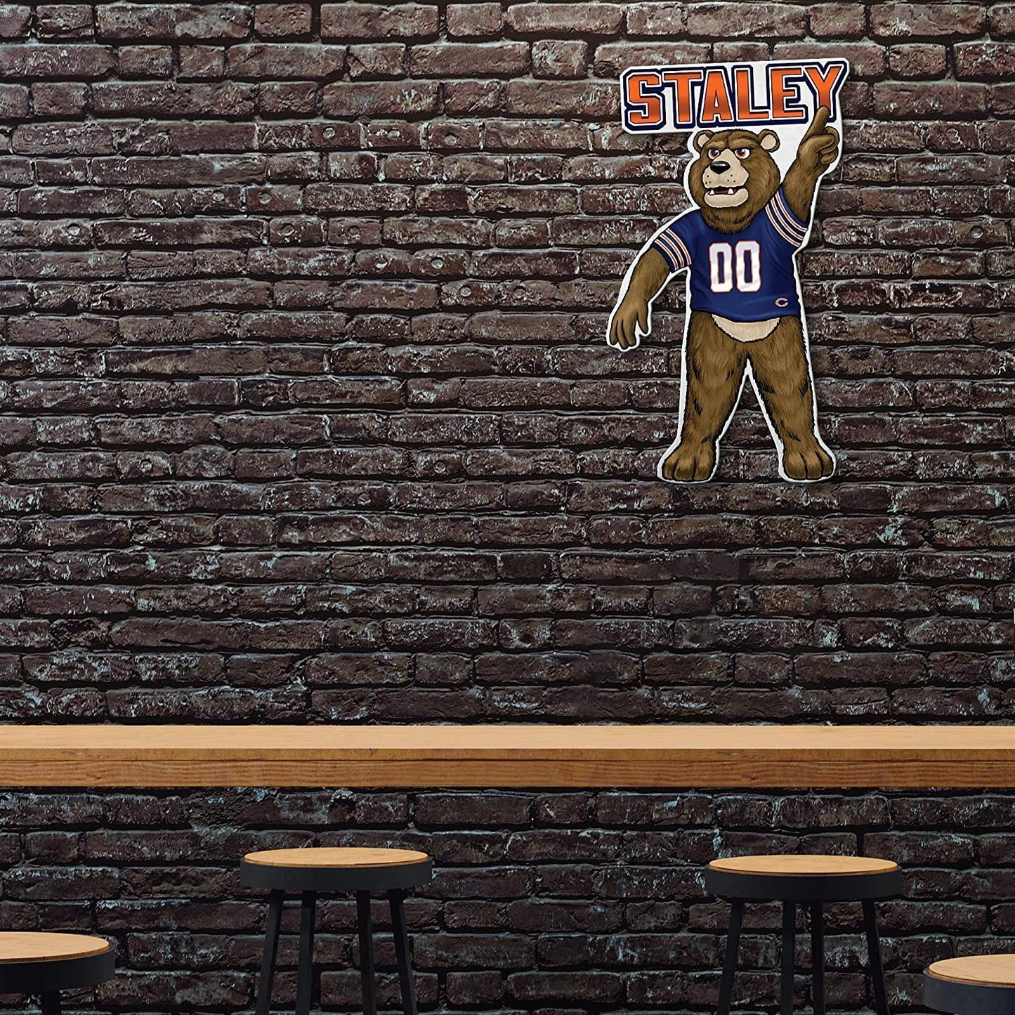 Brick wall with Chicago bear mascot cutout labeled 'Staley' above a bar counter.