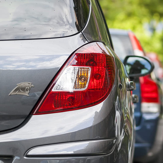 Close-up of a car's tail light with a visible brand logo, blurred background
